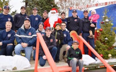 Caption: Lockwood Fire Chief John Staley posing with Santa along with his crew and volunteers at Canary and Bluebird in Lockwood during one of the visits. It takes a crew of about a dozen people to prep, help, take down and then move the Santa set from location to location. (Photo by Jonathan McNiven)