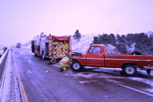 Damaged 1968 F-100 pickup truck with frontend damage due to slippery road conditions on Wednesday Nov. 25th on Yellowstone River bridge on Interstate 90. Fire fighters are hooking to the pickup in order to pull it off the interstate in order for traffic to start moving again on the Interstate. 