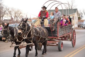 Happy Pappy, front left, of Western Romance Company giving free mule-drawn wagon rides to Keith Rauch, front right, of Shepherd, and his family last year at the Huntley Christmas Stroll. Free wagon rides will be available in Huntley from noon – 4 p.m. Saturday, Dec. 19, weather permitting. (Jonathan McNiven Photo) 