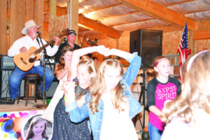 Kamrey Leiser, center, takes a turn on the dance floor with Macey McCann as Kirk Brumfield and Joe Link play with the Bucky Beaver Ground Grippers on Sunday. Also dancing are Hailey Mathews and Bailey Hofmann. (Judy Killen photo)