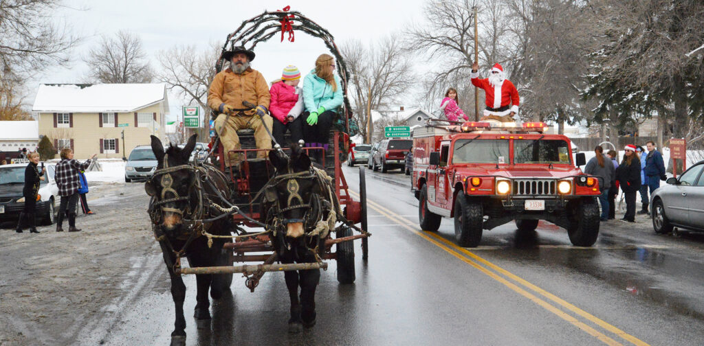 Happy Pappy with Western Romance Company gives strollers free wagon rides along Huntley's Main street while Santa passes wagon riders in the Worden Fire Truck on his way to the Huntley Fire Station. Click on image to enlarge. (Photo by Jonathan McNiven-Yellowstone County News.)